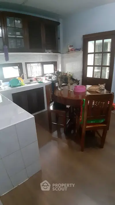 Cozy kitchen with wooden cabinets and dining table, featuring a closed layout and natural light.