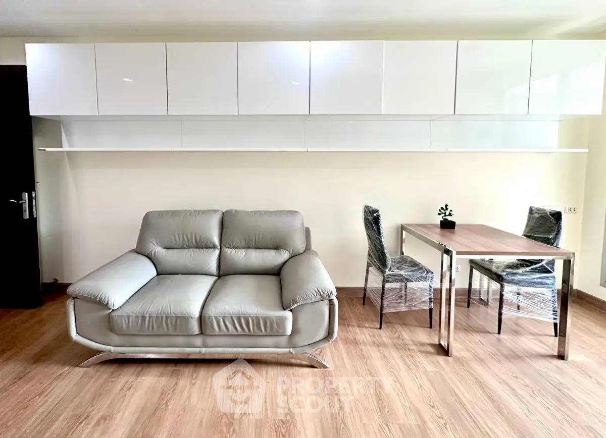 Modern living room with sleek sofa and dining area, featuring minimalist design and wooden flooring.