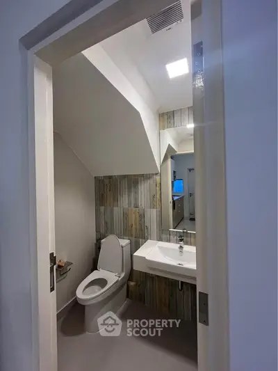 Modern compact bathroom with unique wood paneling and sleek fixtures