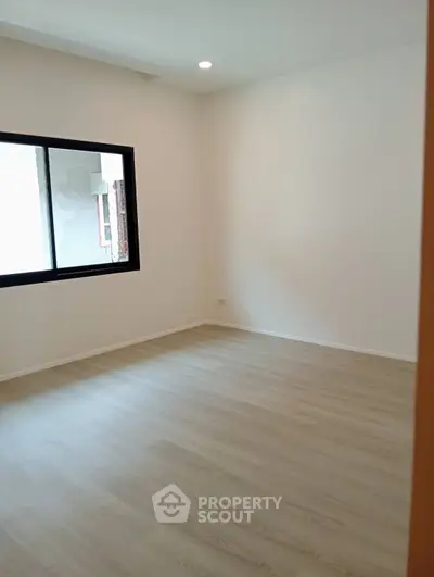 Spacious empty room with wooden flooring and large window