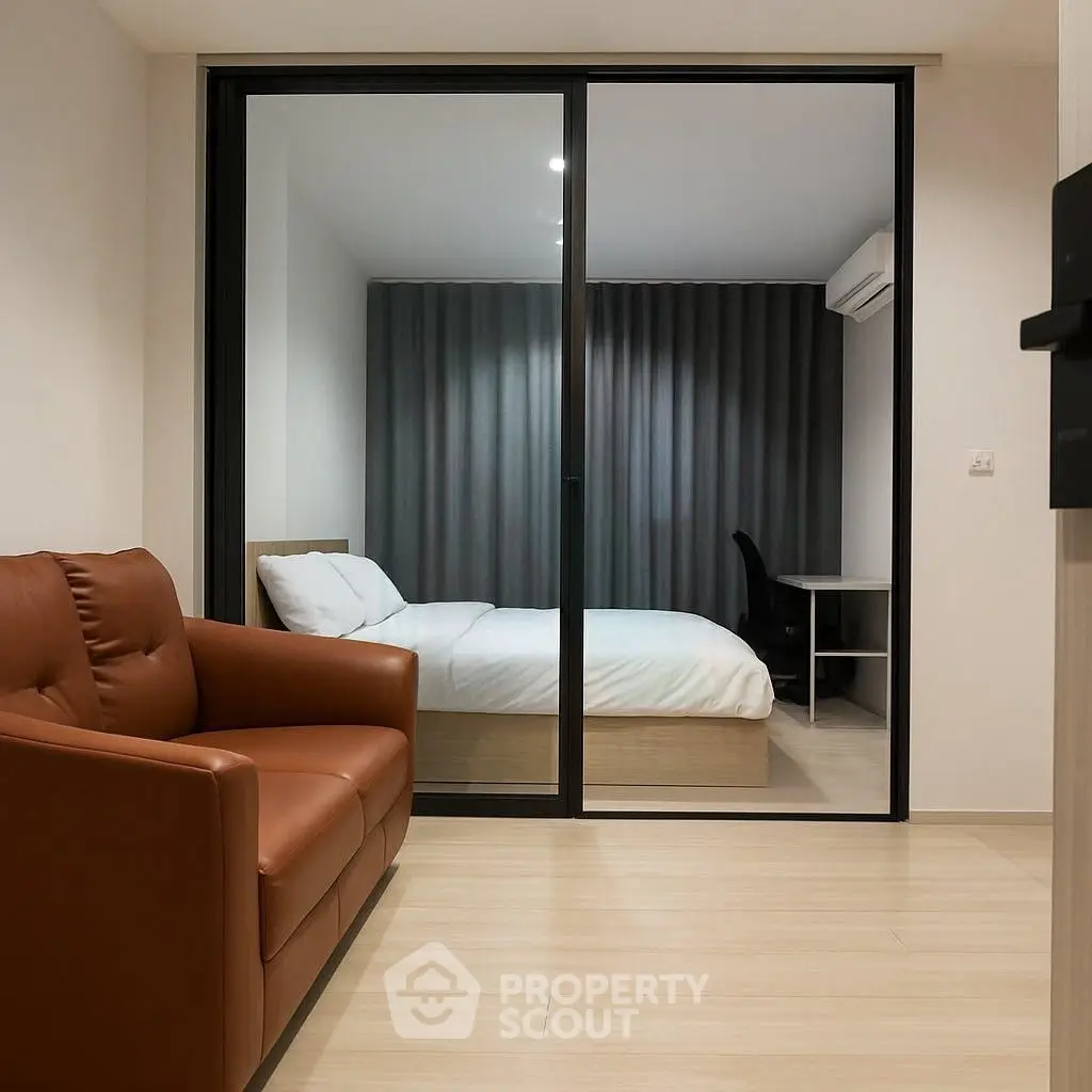 Modern apartment interior with cozy living room and stylish bedroom separated by glass doors.