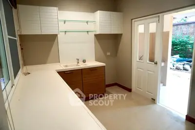 Spacious kitchen with modern cabinetry and open layout leading to outdoor area.