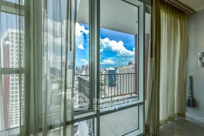 Stunning city view from a modern apartment balcony with glass doors and curtains.