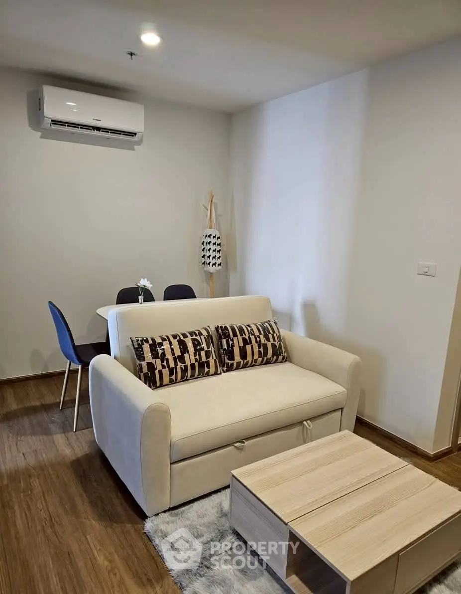 Modern living room with cozy sofa and dining area, featuring elegant decor and air conditioning.