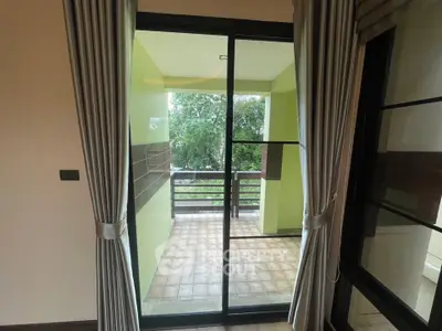 Spacious balcony with sliding glass doors and lush green view, perfect for relaxation.