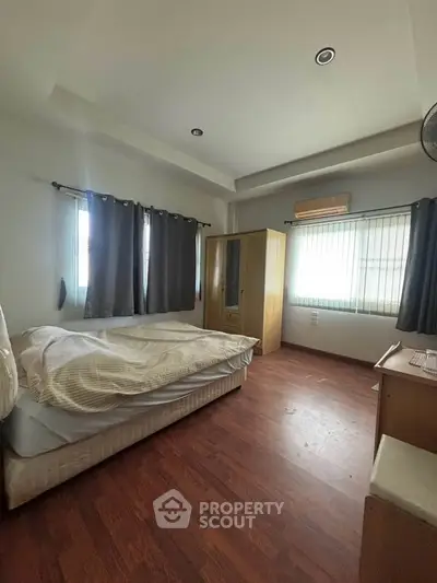 Spacious bedroom with wooden flooring and ample natural light