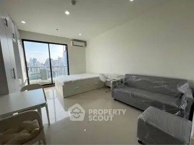 Modern studio apartment with city view, featuring a cozy living area and large windows for natural light.