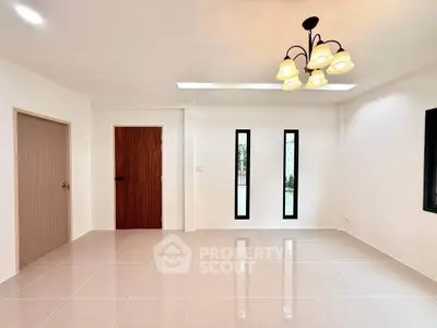 Spacious minimalist living room with modern lighting and sleek tile flooring.