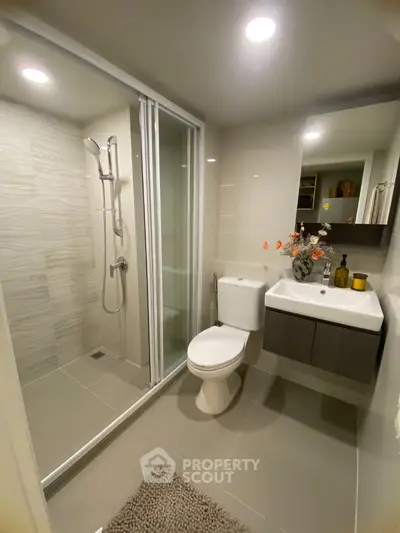 Modern bathroom with glass shower and sleek fixtures in contemporary apartment.