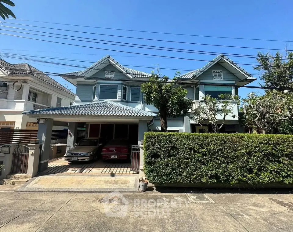 Charming two-story house with lush greenery and spacious driveway in a serene neighborhood.