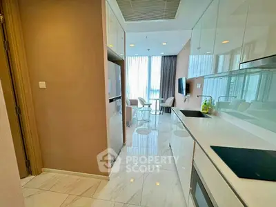 Modern kitchen with sleek cabinetry and open layout leading to a bright dining area.
