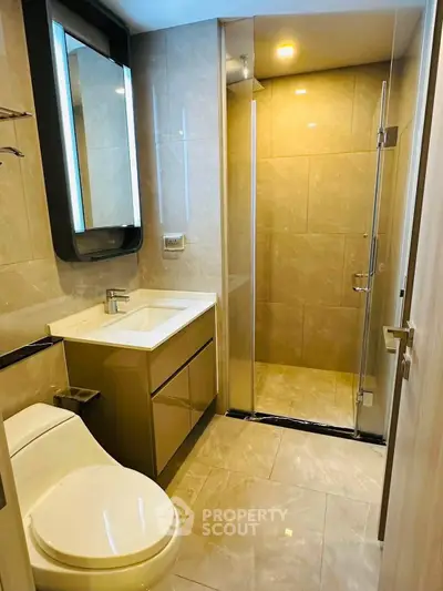 Modern bathroom with sleek design, featuring a glass shower and elegant fixtures.