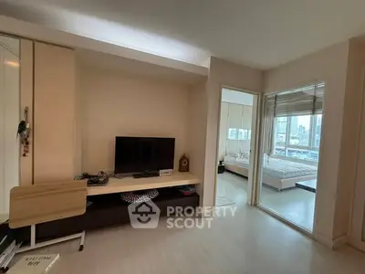 Modern apartment interior with living room and bedroom view, featuring sleek furniture and cityscape window.