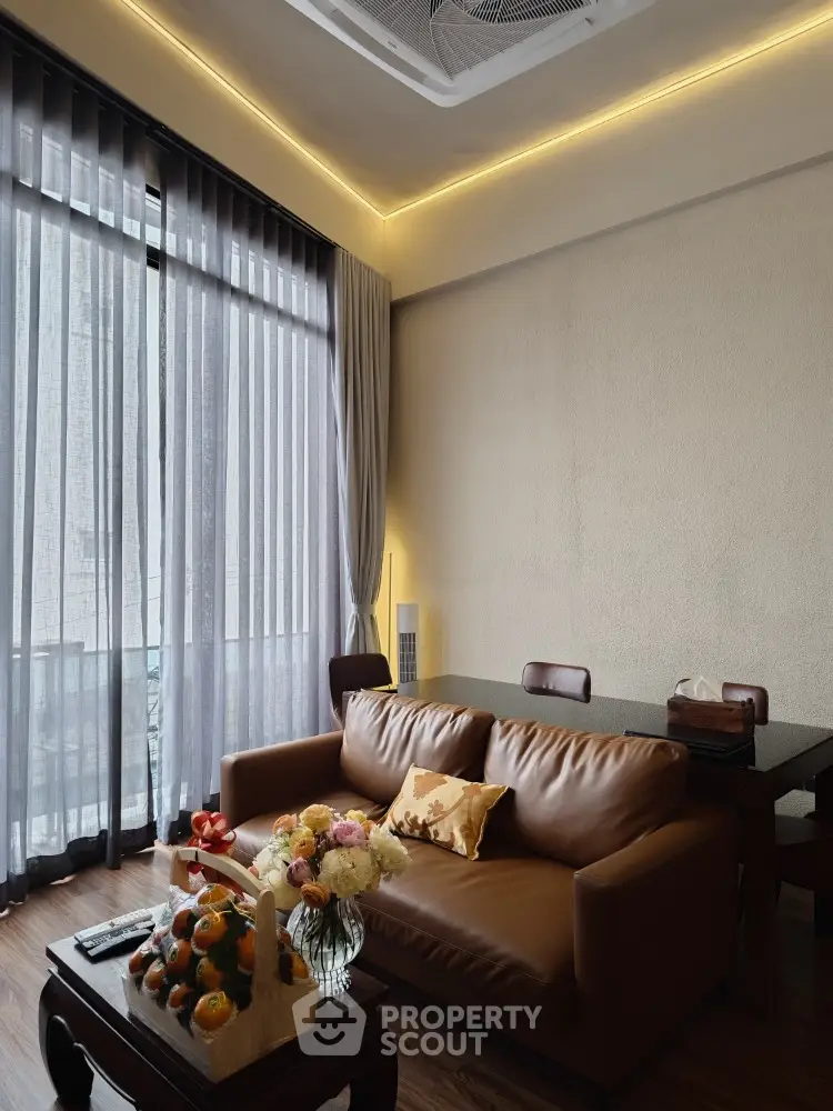 Elegant living room with modern leather sofa, ambient lighting, and floor-to-ceiling windows draped in sheer curtains, creating a warm, inviting atmosphere.