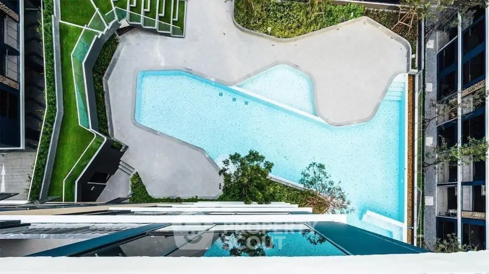 Stunning aerial view of modern apartment complex with luxurious swimming pool and landscaped gardens.