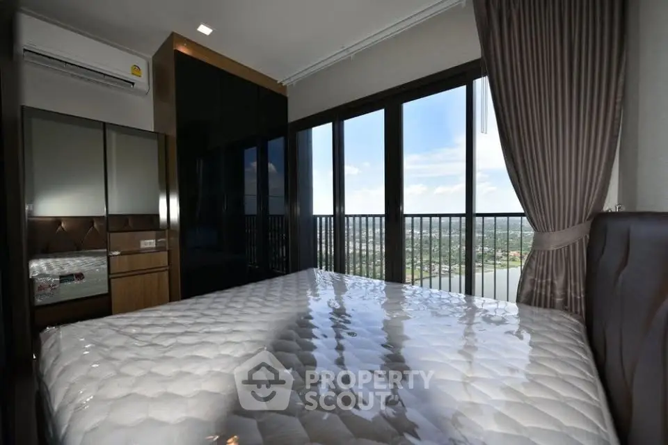 Spacious bedroom with large windows offering stunning city views and modern furnishings.