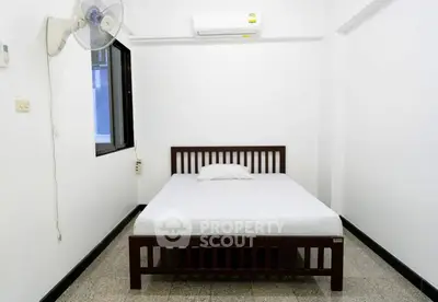 Minimalist bedroom with wooden bed frame and air conditioning unit