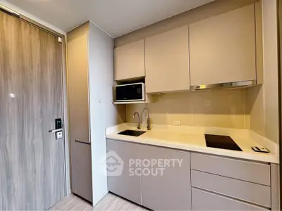 Modern compact kitchen with sleek cabinetry and built-in appliances in a stylish apartment.