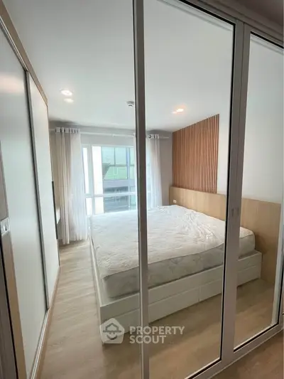 Modern bedroom with large windows and stylish wooden accents in a contemporary apartment.