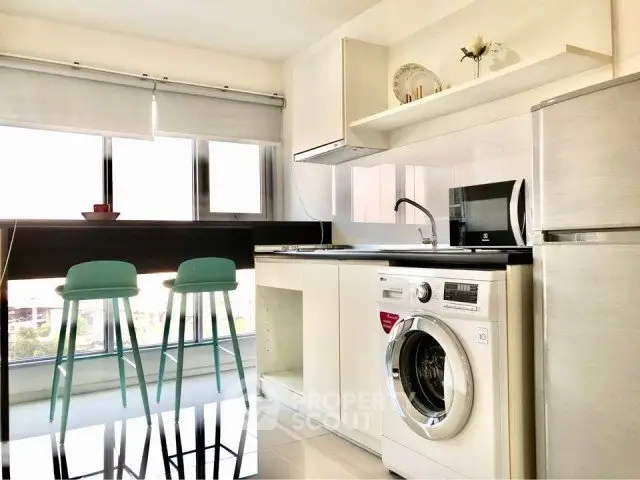 Modern kitchen with washing machine, sleek appliances, and bright natural light.