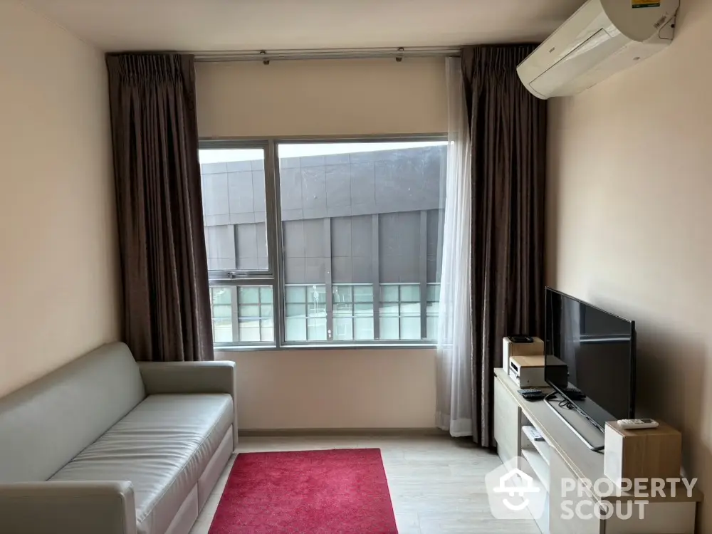 Modern living room with sleek sofa, red rug, and wall-mounted air conditioning