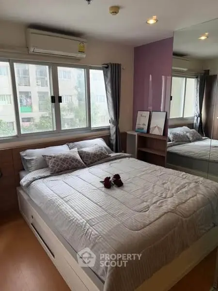 Cozy bedroom with large window and modern decor in urban apartment.