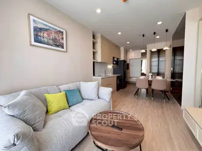 Modern living room with cozy sofa, vibrant cushions, and sleek kitchen in open layout apartment.