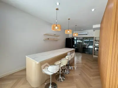 Modern kitchen with sleek island, stylish pendant lights, and elegant bar stools in a contemporary home.