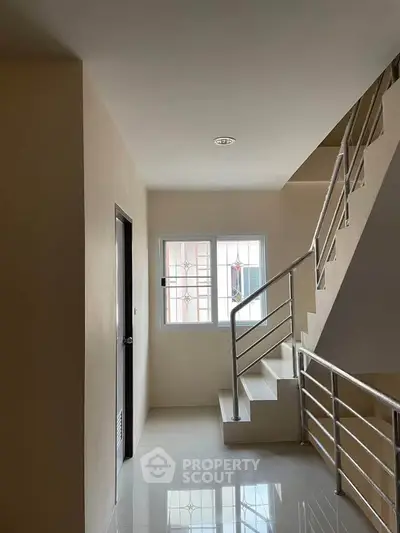 Modern stairwell with sleek metal railings and natural light from window