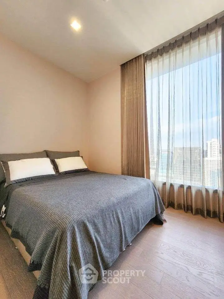 Modern bedroom with large window offering stunning city view and elegant decor.