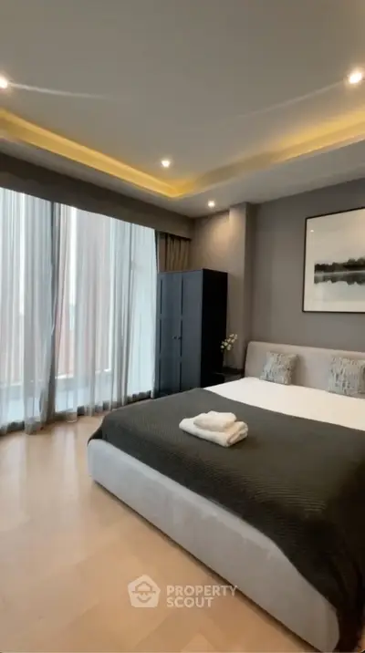 Luxurious bedroom with modern decor and large windows offering natural light