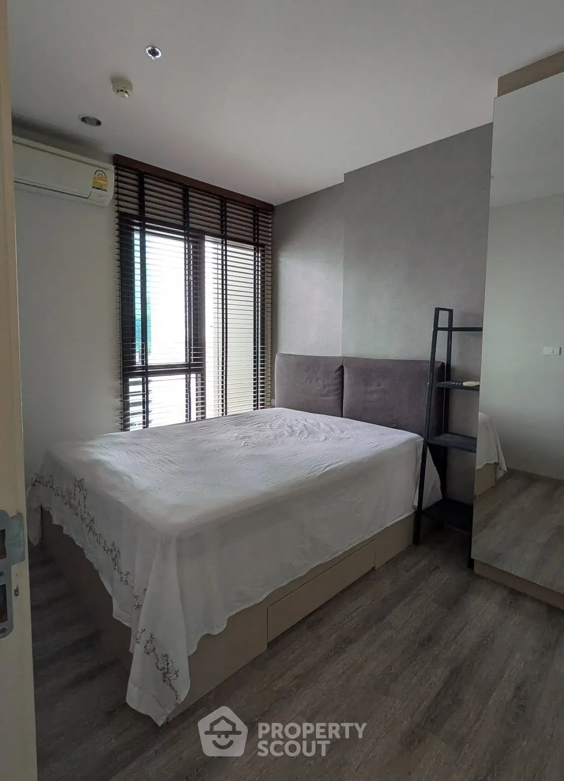Modern bedroom with large window and stylish decor in a contemporary apartment.