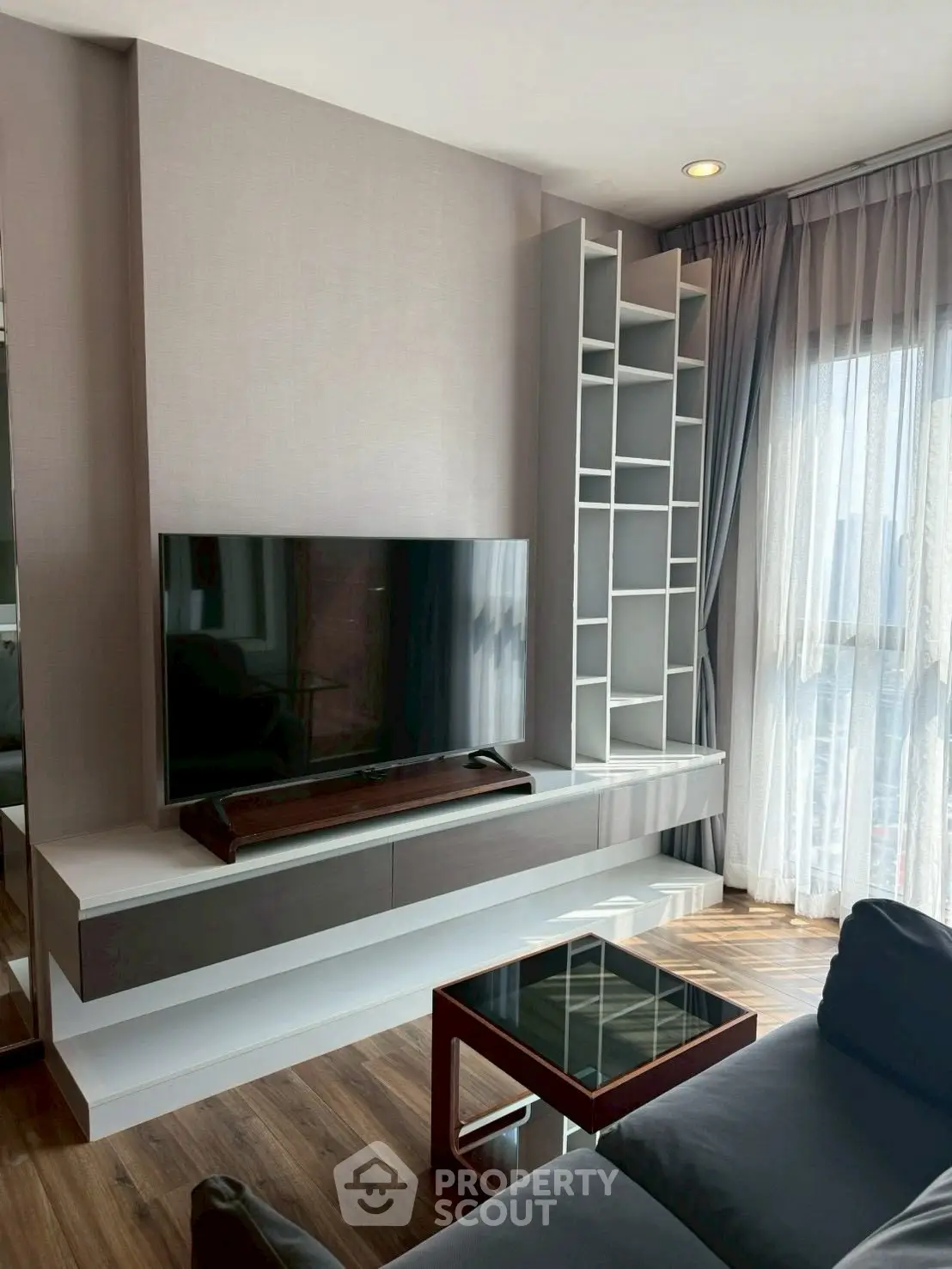 Modern living room with sleek TV unit and large window for natural light.