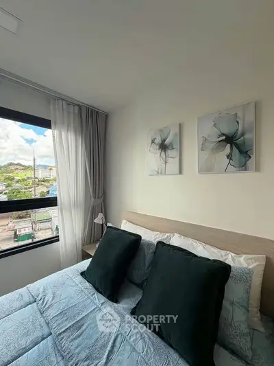 Cozy bedroom with elegant decor and large window offering scenic city views, perfect for relaxation.