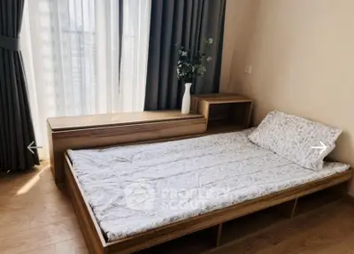 Cozy bedroom with wooden flooring and large window for natural light.