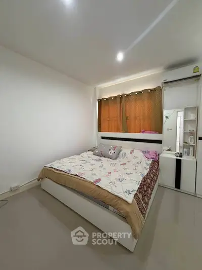 Cozy bedroom with modern decor and ample natural light, perfect for relaxation and comfort.