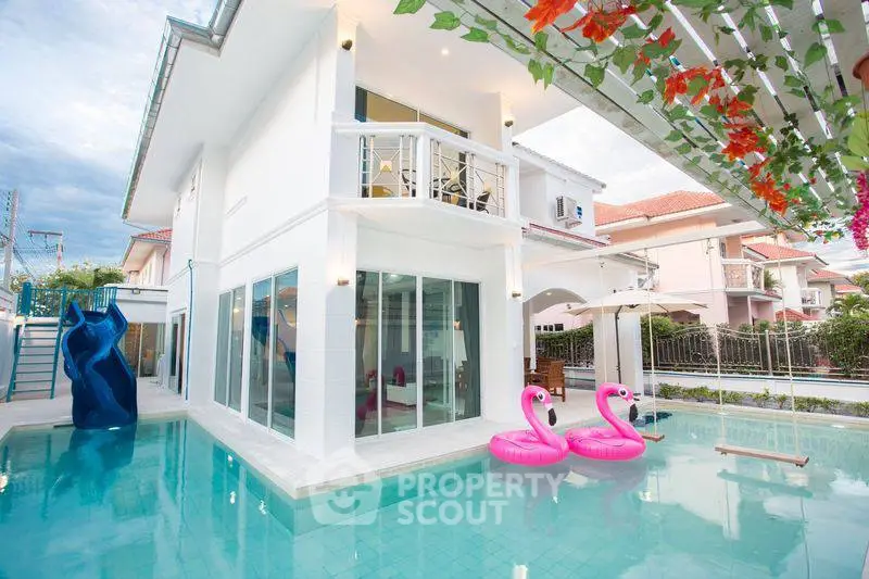 Luxurious modern villa with pool and balcony, featuring playful flamingo floats.