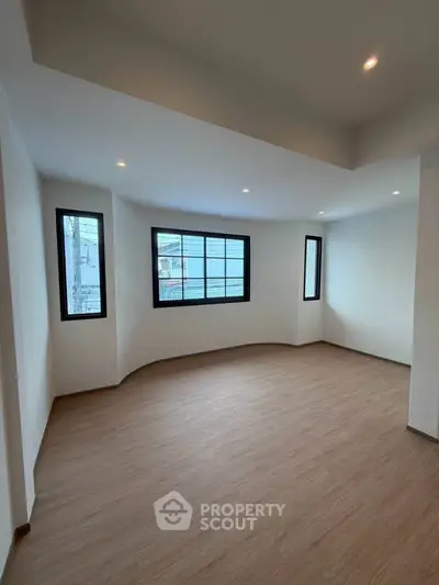 Spacious empty room with large windows and wooden flooring, perfect for customization.