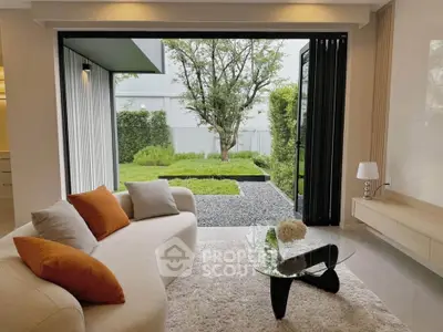 Luxurious living room with garden view, featuring modern furniture and large glass doors opening to a lush backyard.