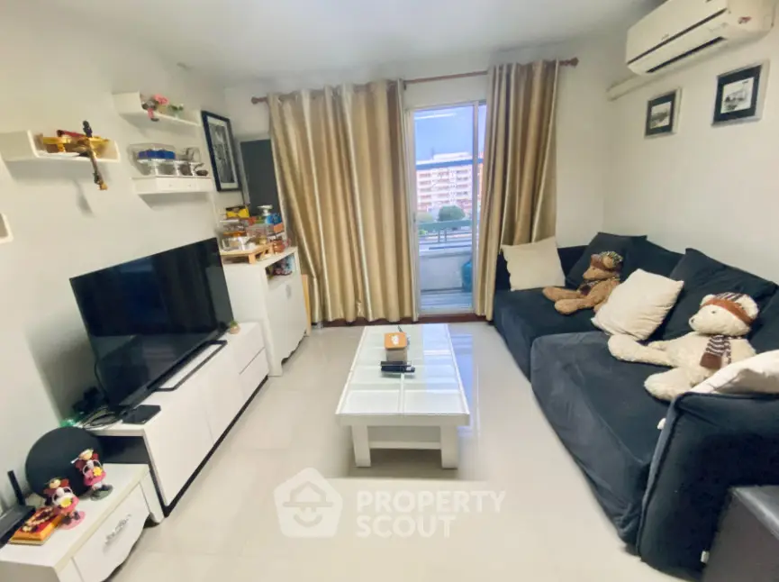 Cozy living room with modern decor, large window, and comfortable seating, perfect for relaxation.