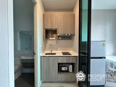 Modern compact kitchen with wooden cabinets and integrated appliances in a stylish apartment.