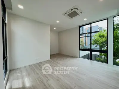Spacious modern living room with large windows and sleek flooring, offering abundant natural light and a serene view.