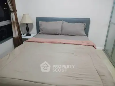 Cozy bedroom with modern decor and large window offering natural light.