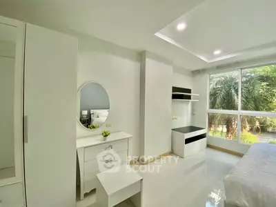 Bright and modern bedroom with large window and sleek white furniture.