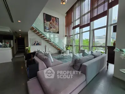 Luxurious modern living room with high ceilings, large windows, and stylish decor in a contemporary apartment.