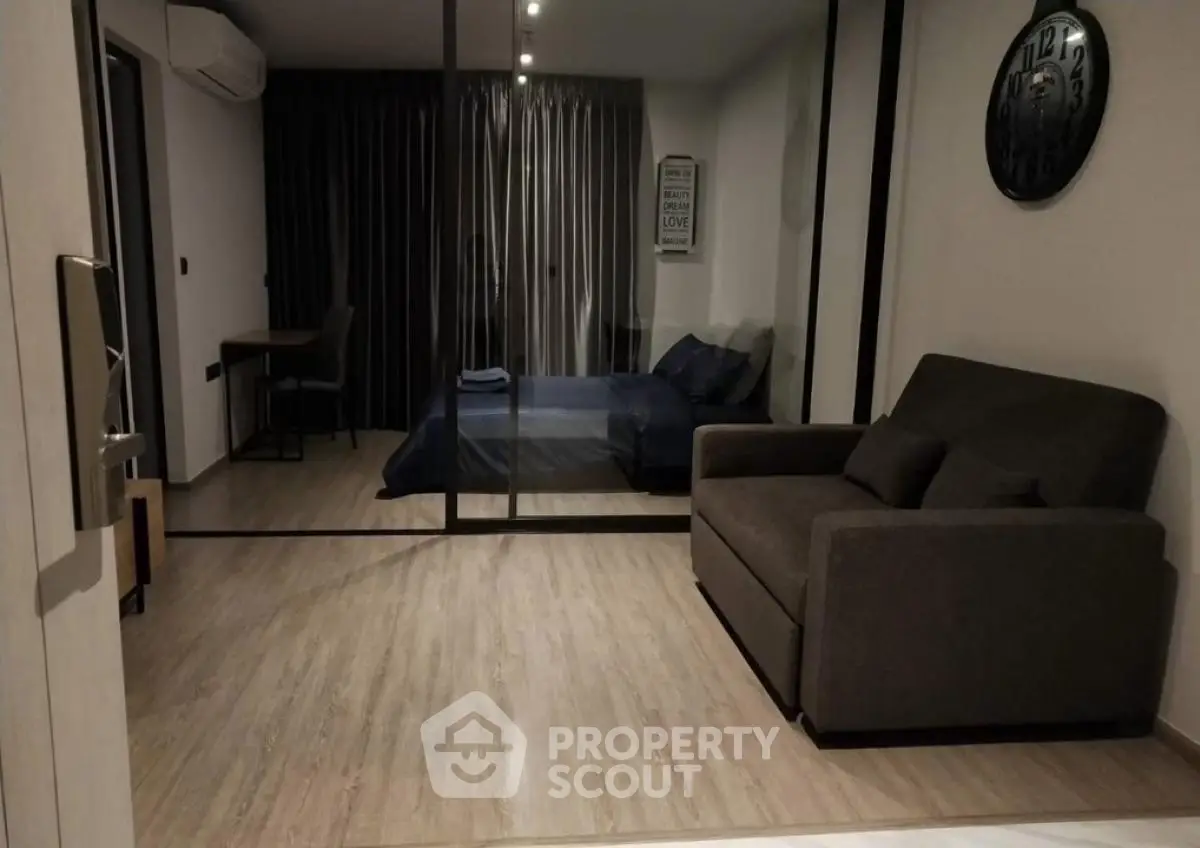 Modern studio apartment with cozy living area and bedroom separated by glass partition.
