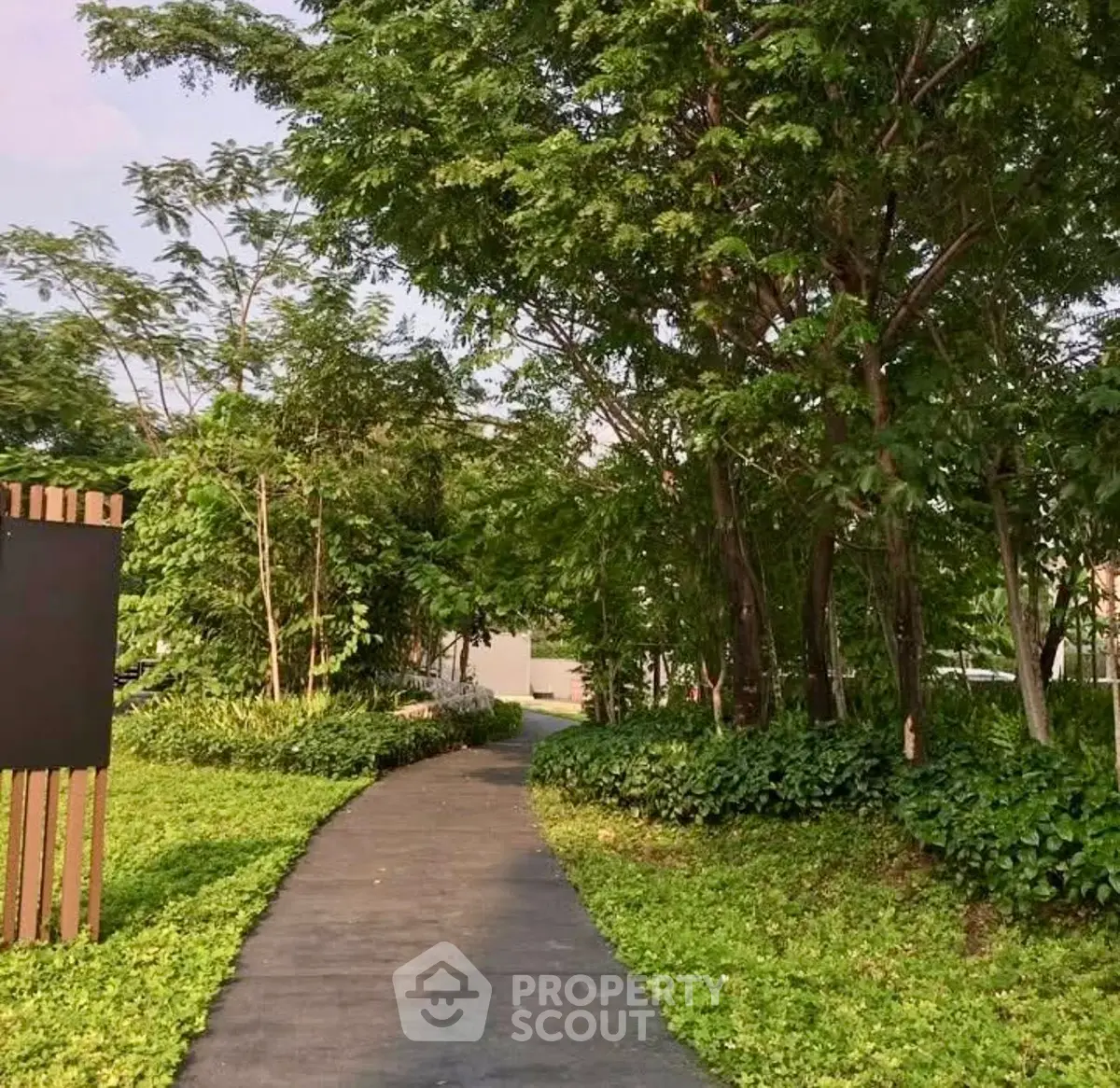 Serene garden pathway surrounded by lush greenery in a residential complex.
