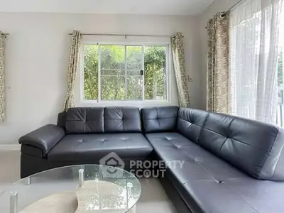 Spacious living room with modern black leather sectional sofa and large windows.