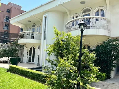 Elegant two-story building with lush garden and unique arched windows