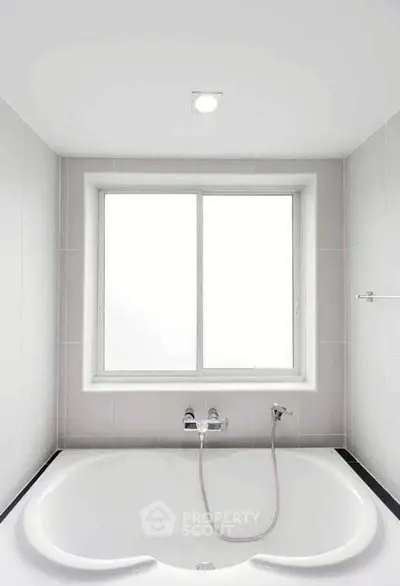Modern bathroom with large bathtub and bright window, perfect for relaxation.